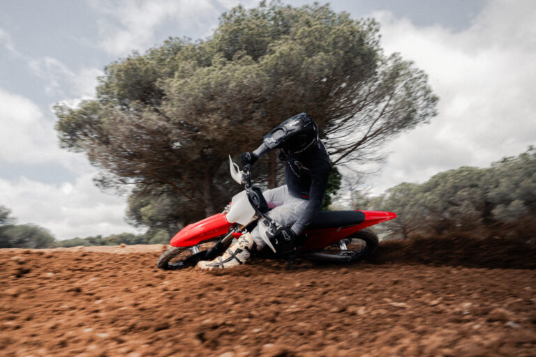 Stark Future selects Dunlop tires for Varg MX Dunlop’s Geomax MX34 on Stark Future Varg MX motorcross bike, shown here pefforming a sliding lefthand turn on a dirt road with a tree in the background.