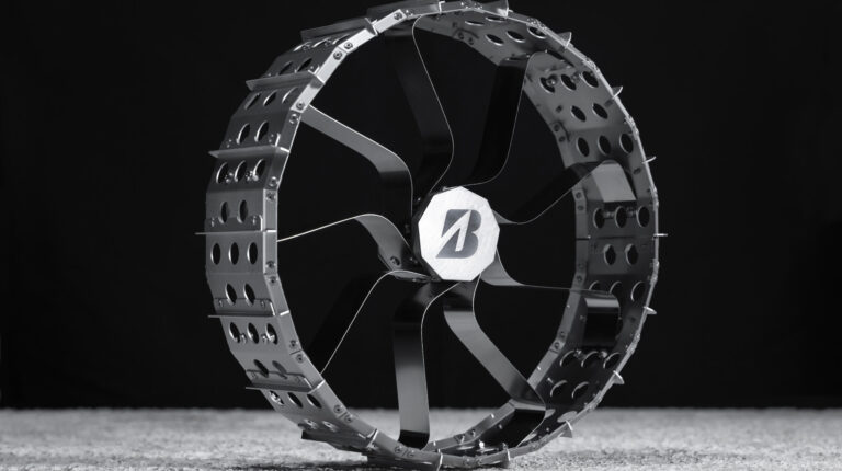 A wheel for a lunar rover shown in profile on a grey floor with a black background