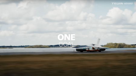 The Nuna 13 race car drives at speed on a test track under cloudy grey skies