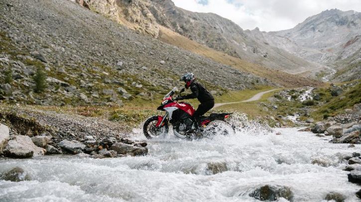 Continental launches off-road and supersport tires A motorcyclist rides across a small stream in a mountainous landscape