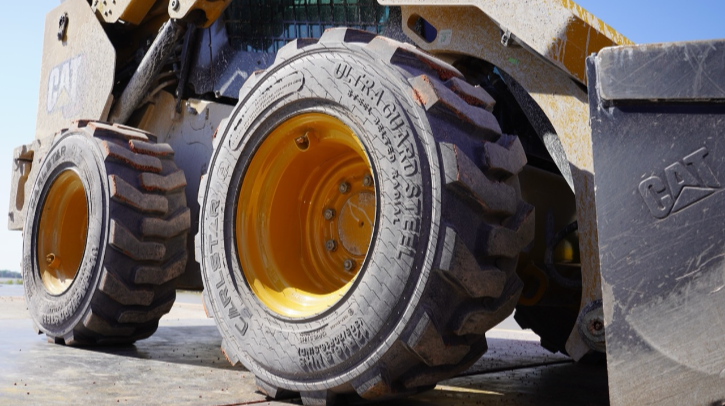 A close up of Titan's steel-belted skid steer tire on a large construction vehicle