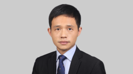 Profile photo of Henry He, Smithers’ general manager of the materials science and engineering division for Asia-Pacific. He is wearing a light blue shirt, a dark tie and a dark suit and is standing against a light grey background
