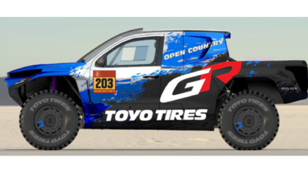 The DKR GR Hilux with a predominantly black and blue livery, has red and white writing down the side that says 'Toyo Tire'.