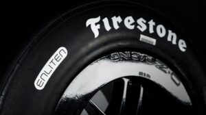 A black tire with Firestone and Enliten written along the sidewall in white.