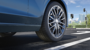 A close up of a tire on a blue sports car parked on a roadside on a bright sunny day.
