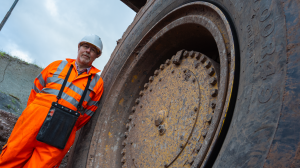 Bridgestone’s Rob Cole, key account manager – off-road tires, UK and Ireland, stands in front of a Bridgestone mining tire on a large off-road machine.