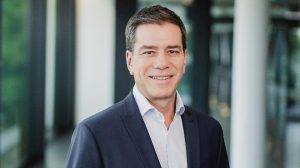 Jorge Almeida, head of sustainability for Continental's Tires sector in a profile photo. He is wearing a dark blue suit and a white shirt and is standing in an office.