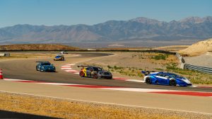 Race cars drive around a track at a Racine America motorsports event.